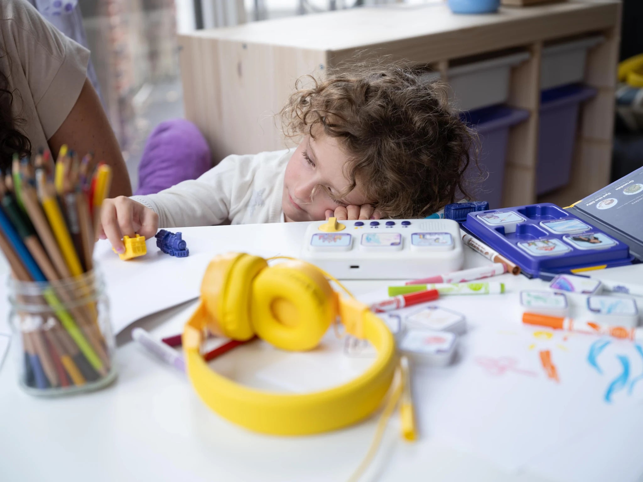 A child resting beside a storymaker and yellow headphones.