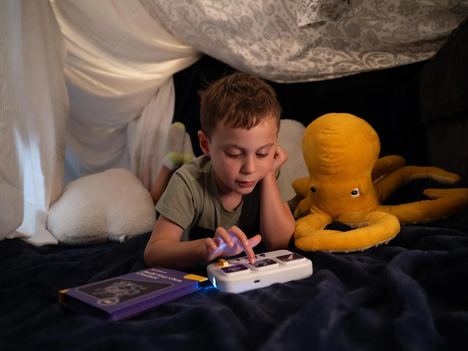 A child listening to storymaker under a blanket fort