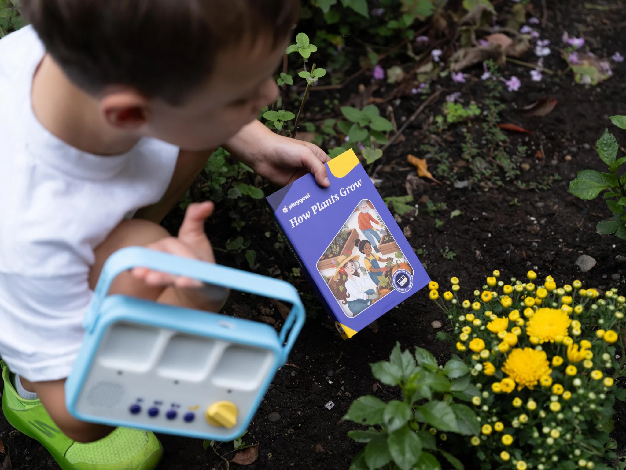 A child carries a storymaker and How Plants Grow book outside.