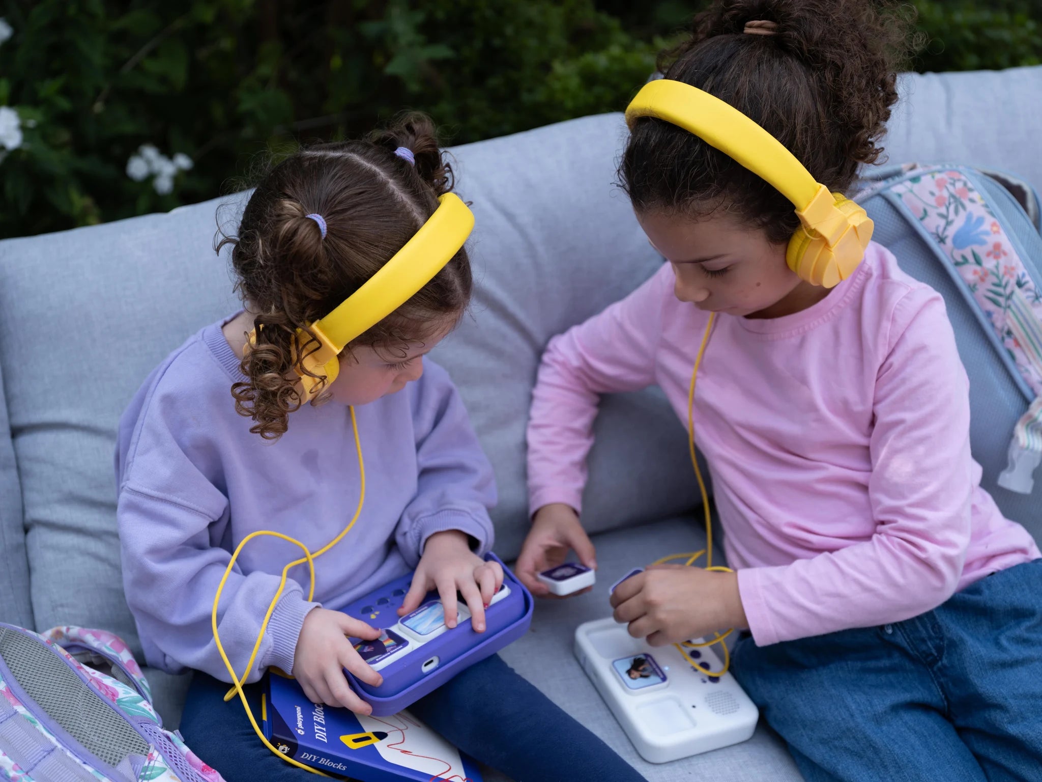 Two children listen to their stories with headphones.